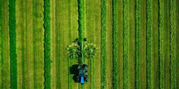 Aerial view of Tractor mowing green field in Finland.